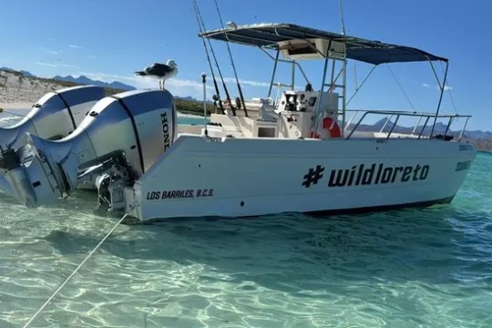 Boat with hashtag #wildloreto docked in clear turquoise water.
