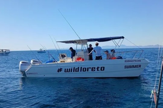 Boat named 'wildloreto' on ocean with four people on board.